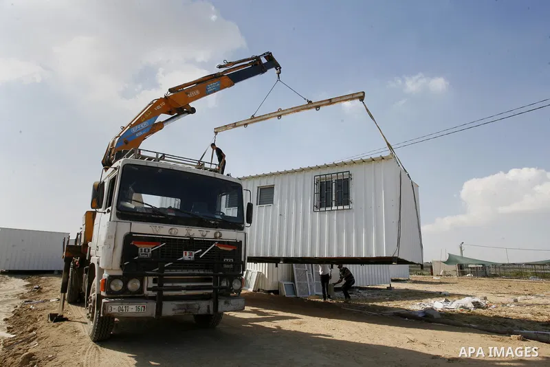 Workers place containers donated by Human Appeal for Palestinians, as temporary replacements for the houses that were destroyed during a seven-week Israeli offensive, in the east of Khan Younis in the southern Gaza Strip...