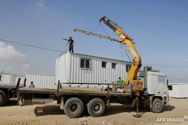 Workers place containers donated by Human Appeal for Palestinians, as temporary replacements for the houses that were destroyed during a seven-week Israeli offensive, in the east of Khan Younis in the southern Gaza Strip...