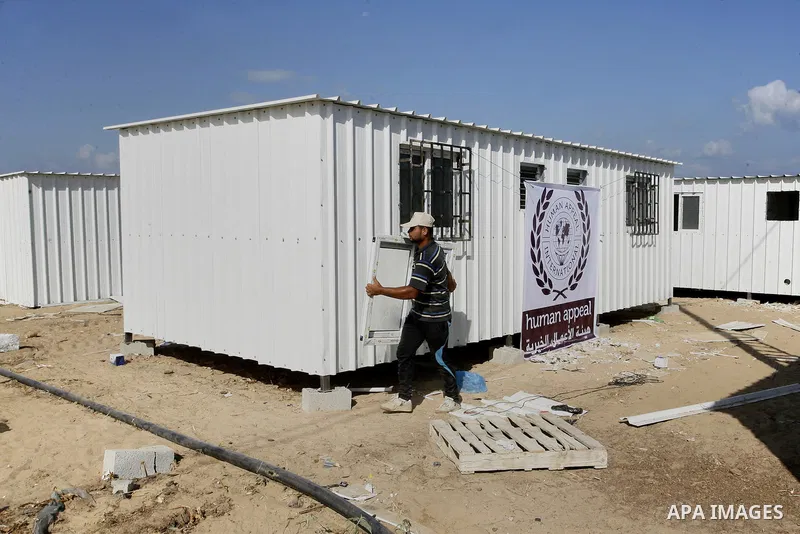 Workers place containers donated by Human Appeal for Palestinians, as temporary replacements for the houses that were destroyed during a seven-week Israeli offensive, in the east of Khan Younis in the southern Gaza Strip...