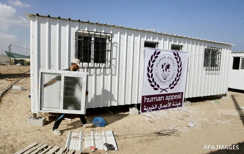 Workers place containers donated by Human Appeal for Palestinians, as temporary replacements for the houses that were destroyed during a seven-week Israeli offensive, in the east of Khan Younis in the southern Gaza Strip...