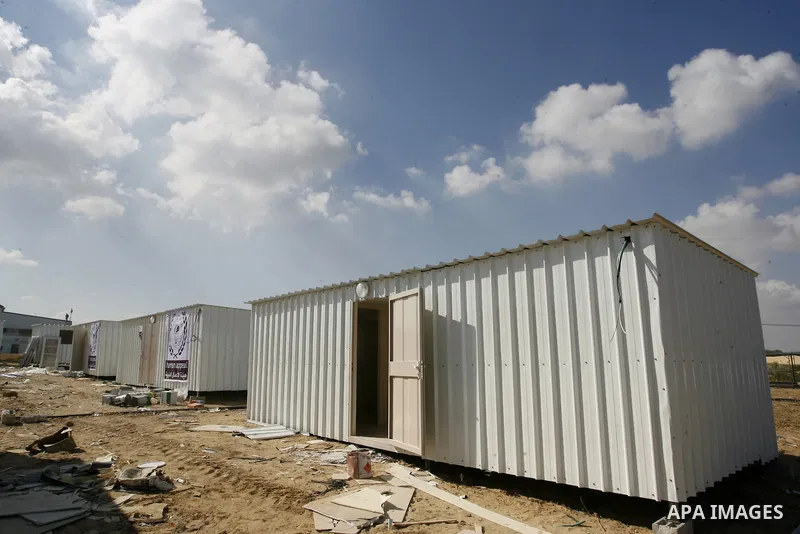 Workers place containers donated by Human Appeal for Palestinians, as temporary replacements for the houses that were destroyed during a seven-week Israeli offensive, in the east of Khan Younis in the southern Gaza Strip...
