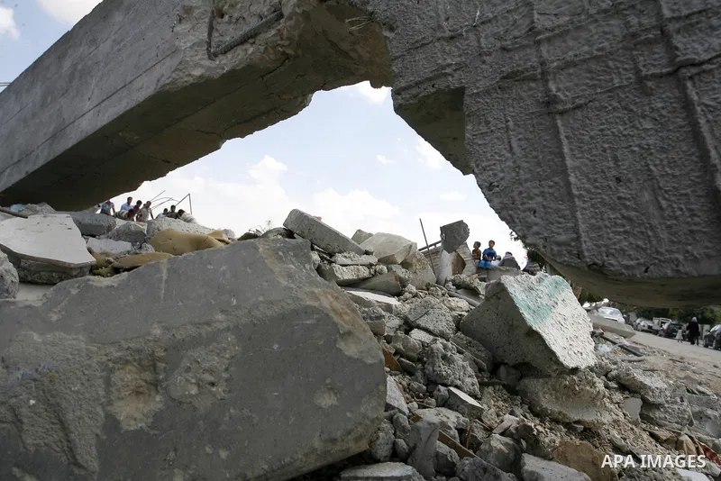 Palestinians sit on atop the ruins of houses, which witnesses said was destroyed by an Israeli air strike during a seven-week offensive, in the east of Khan Younis in the southern Gaza Strip September 13, 2014. An open-e...