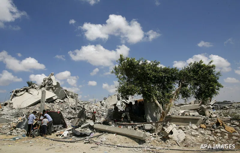 Palestinians sit on atop the ruins of houses, which witnesses said was destroyed by an Israeli air strike during a seven-week offensive, in the east of Khan Younis in the southern Gaza Strip September 13, 2014. An open-e...