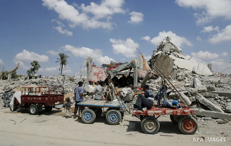 A Palestinian man rides a donkey cart past the ruins of houses, which witnesses said was destroyed by an Israeli air strike during a seven-week offensive, in the east of Khan Younis in the southern Gaza Strip September 1...