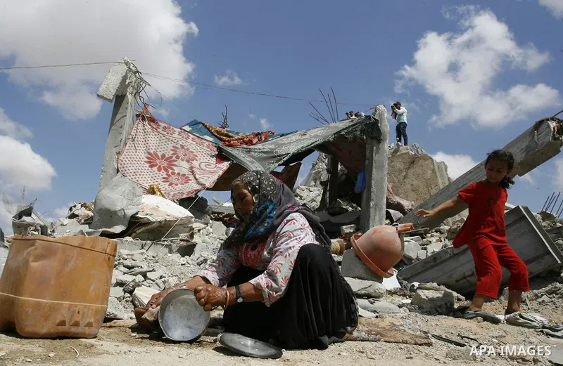 A Palestinian woman washs the dishes atop the ruins of her house, which witnesses said was destroyed by an Israeli air strike during a seven-week offensive, in the east of Khan Younis in the southern Gaza Strip September...