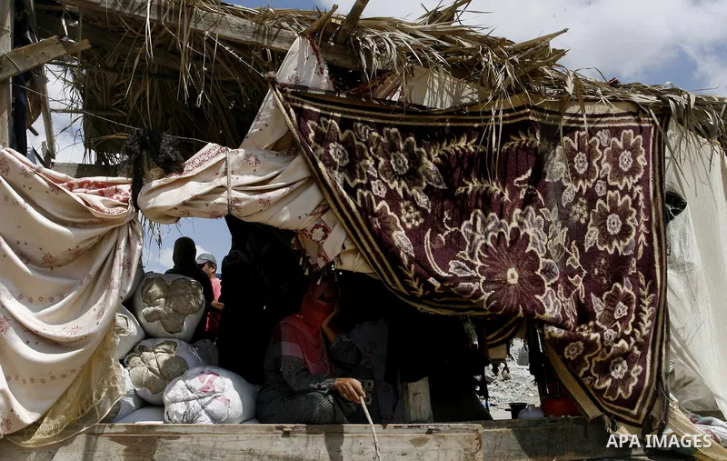 Palestinians sits under a tent on the ruins of their house, which witnesses said was destroyed by an Israeli air strike during a seven-week offensive, in the east of Khan Younis in the southern Gaza Strip September 13, 2...
