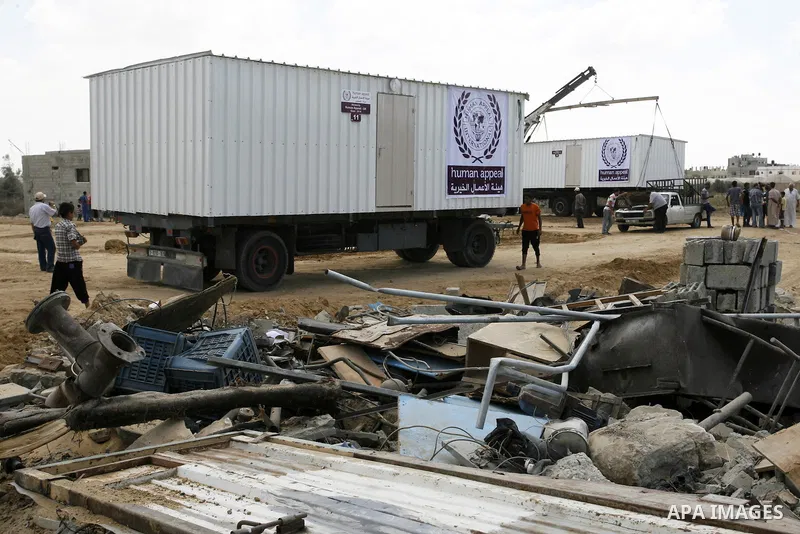 Workers place containers donated by Human Appeal for Palestinians, as temporary replacements for the houses that were destroyed during a seven-week Israeli offensive, in the east of Khan Younis in the southern Gaza Strip...