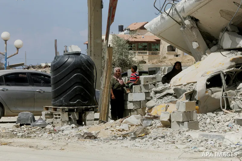 Palestinians stand past the ruins of their house, which witnesses said was destroyed by an Israeli air strike during a seven-week offensive, in the east of Khan Younis in the southern Gaza Strip September 13, 2014. An op...