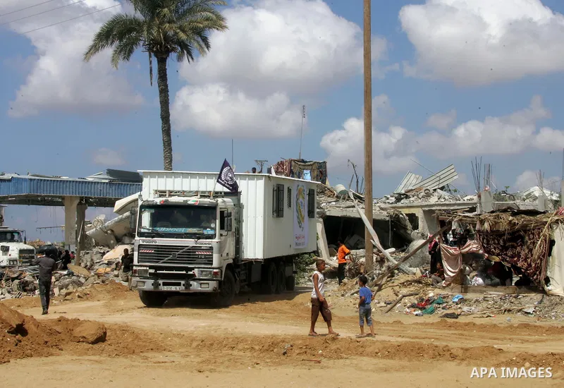 Workers place containers donated by Human Appeal for Palestinians, as temporary replacements for the houses that were destroyed during a seven-week Israeli offensive, in the east of Khan Younis in the southern Gaza Strip...