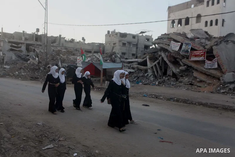 Palestinian students walk past houses that witnesses said were destroyed by the Israeli offensive, as they make their way to school on the first day of the new school year in the east of Gaza City September 14, 2014. An...
