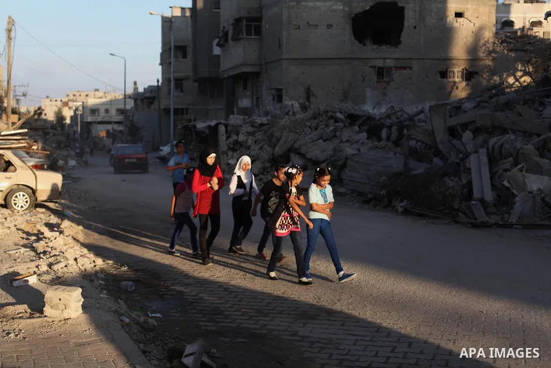 Palestinian students walk past houses that witnesses said were destroyed by the Israeli offensive, as they make their way to school on the first day of the new school year in the east of Gaza City September 14, 2014. An...