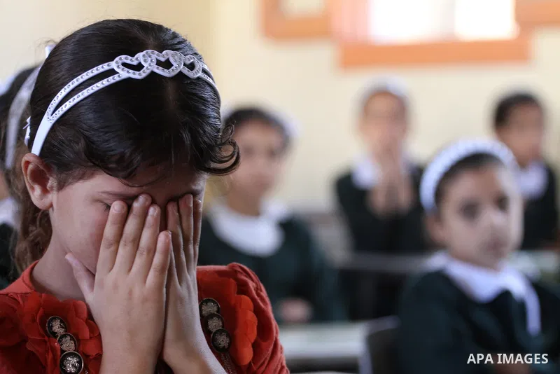 Palestinian students cry on the students who were killed during the Israeli offensive inside their school that witnesses said was shelled by Israel during its offensive, on the first day of the new school year in the eas...