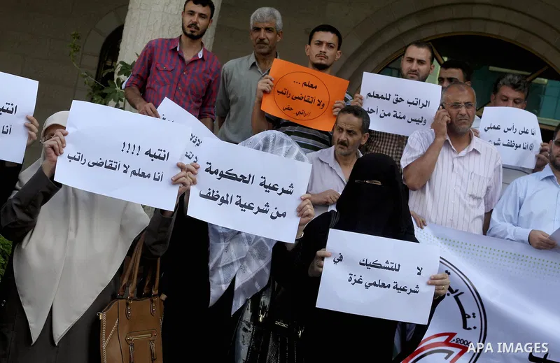 Palestinian Teachers union hold banners during a protest to demand their salaries, on the first day of the new school year in Gaza City September 14, 2014. An open-ended ceasefire between Israel and Hamas-led Gaza milita...