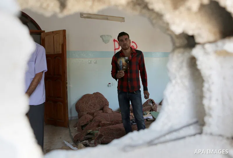 Palestinian Firas Abu Toaimeh, 26, holds a picture of his brother Mohammed Abu Toaimeh, 22, at his house which was hit by Israeli shelling during the war, in Khan Yunis town in the southern Gaza Strip, on September 18, 2...