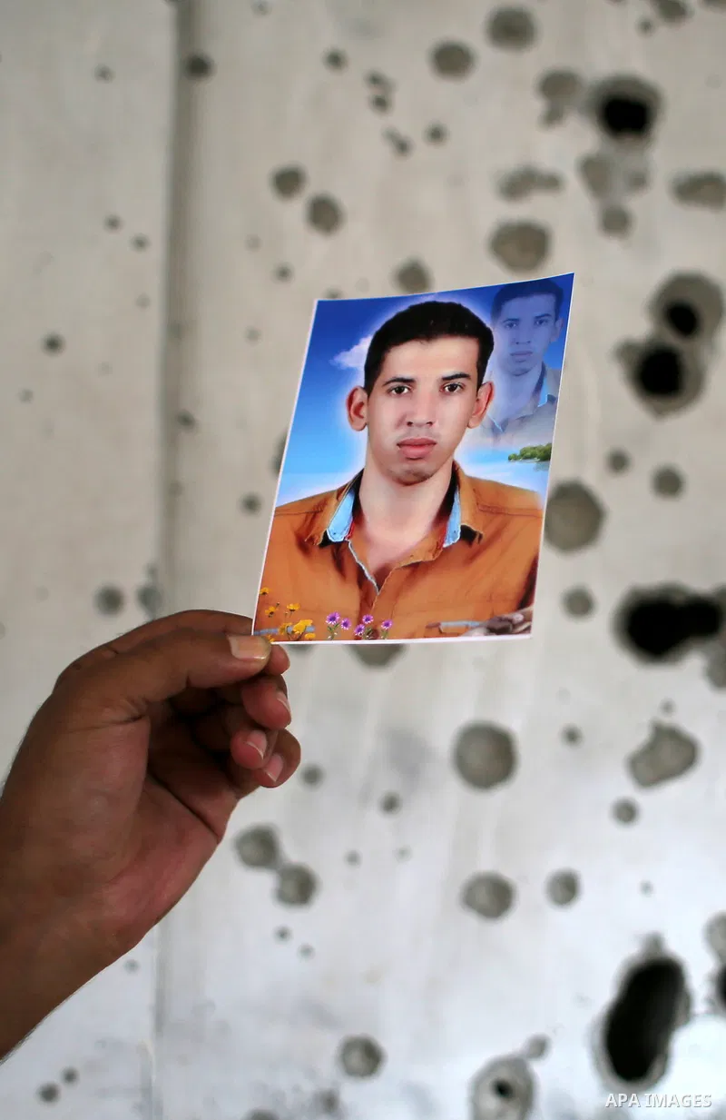Palestinian Ahmed al-Jorf, 17, holds a picture of his brother Hussein al-Jorf, 19, at his house which was hit by Israeli shelling during the war, in Khan Yunis town in the southern Gaza Strip, on September 18, 2014. Huss...