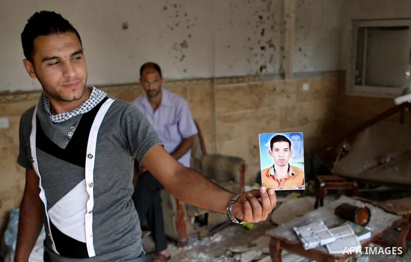 Palestinian friend of Hussein al-Jorf, 19, holds his picture at his house which was hit by Israeli shelling during the war, in Khan Yunis town in the southern Gaza Strip, on September 18, 2014. Hussein al-Jorf, and other...