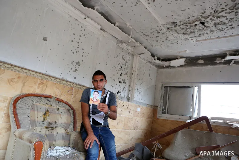 Palestinian friend of Hussein al-Jorf, 19, holds his picture at his house which was hit by Israeli shelling during the war, in Khan Yunis town in the southern Gaza Strip, on September 18, 2014. Hussein al-Jorf, and other...