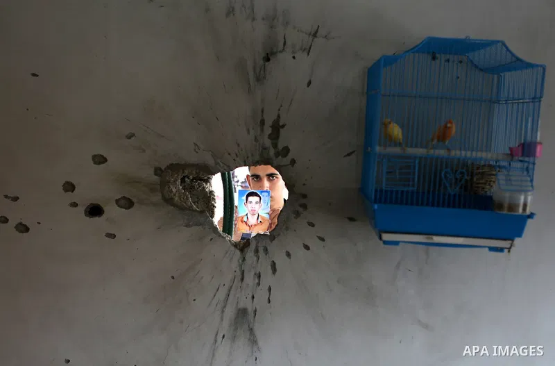 Palestinian Ahmed al-Jorf, 17, holds a picture of his brother Hussein al-Jorf, 19, at his house which was hit by Israeli shelling during the war, in Khan Yunis town in the southern Gaza Strip, on September 18, 2014. Huss...