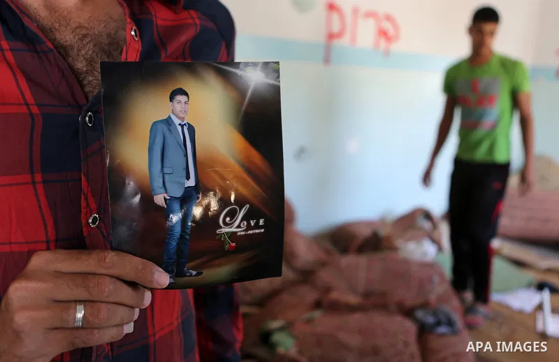 Palestinian Firas Abu Toaimeh, 26, holds a picture of his brother Mohammed Abu Toaimeh, 22, at his house which was hit by Israeli shelling during the war, in Khan Yunis town in the southern Gaza Strip, on September 18, 2...