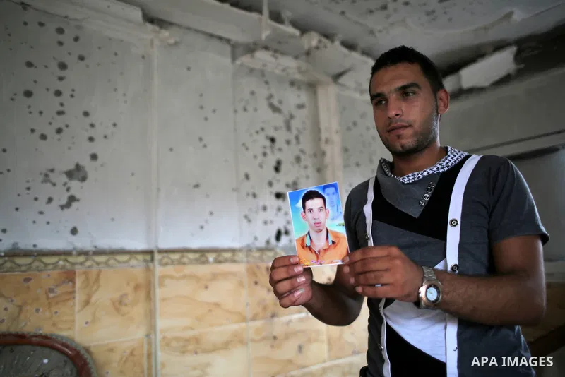 Palestinian friend of Hussein al-Jorf, 19, holds his picture at his house which was hit by Israeli shelling during the war, in Khan Yunis town in the southern Gaza Strip, on September 18, 2014. Hussein al-Jorf, and other...
