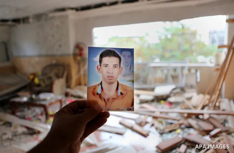 Palestinian Ahmed al-Jorf, 17, holds a picture of his brother Hussein al-Jorf, 19, at his house which was hit by Israeli shelling during the war, in Khan Yunis town in the southern Gaza Strip, on September 18, 2014. Huss...
