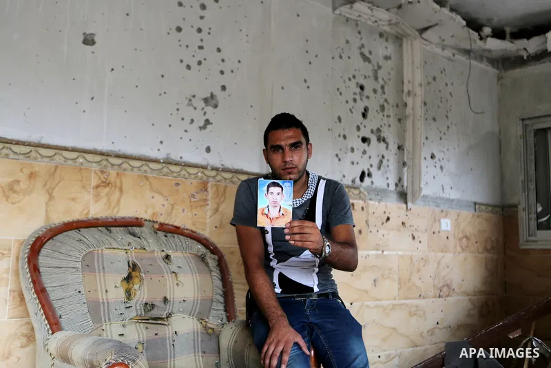 Palestinian friend of Hussein al-Jorf, 19, holds his picture at his house which was hit by Israeli shelling during the war, in Khan Yunis town in the southern Gaza Strip, on September 18, 2014. Hussein al-Jorf, and other...