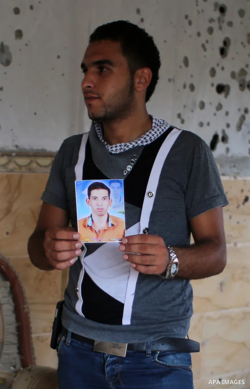 Palestinian friend of Hussein al-Jorf, 19, holds his picture at his house which was hit by Israeli shelling during the war, in Khan Yunis town in the southern Gaza Strip, on September 18, 2014. Hussein al-Jorf, and other...