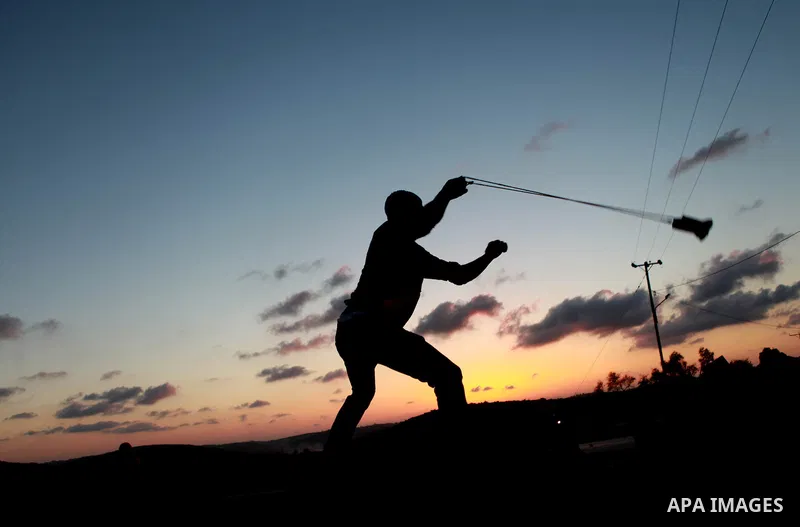 A Palestinian protester throws stones towards Israeli security forces during clashes at a protest against the Jewish settlement of Ofra, in the West Bank village of Silwad, near Ramallah September 19, 2014 . Photo by Sha...