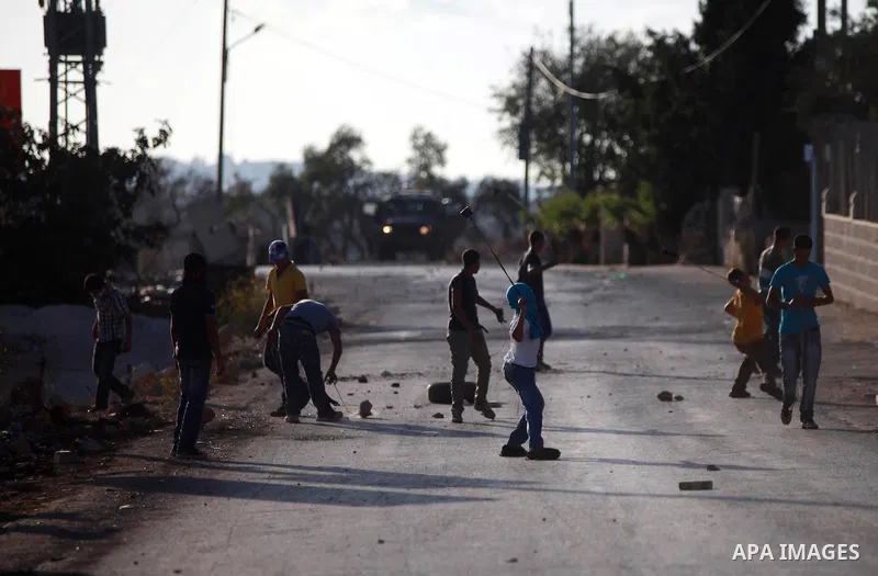 Palestinian protesters throw stones towards Israeli security forces during clashes at a protest against the Jewish settlement of Ofra, in the West Bank village of Silwad, near Ramallah September 19, 2014 . Photo by Shadi...
