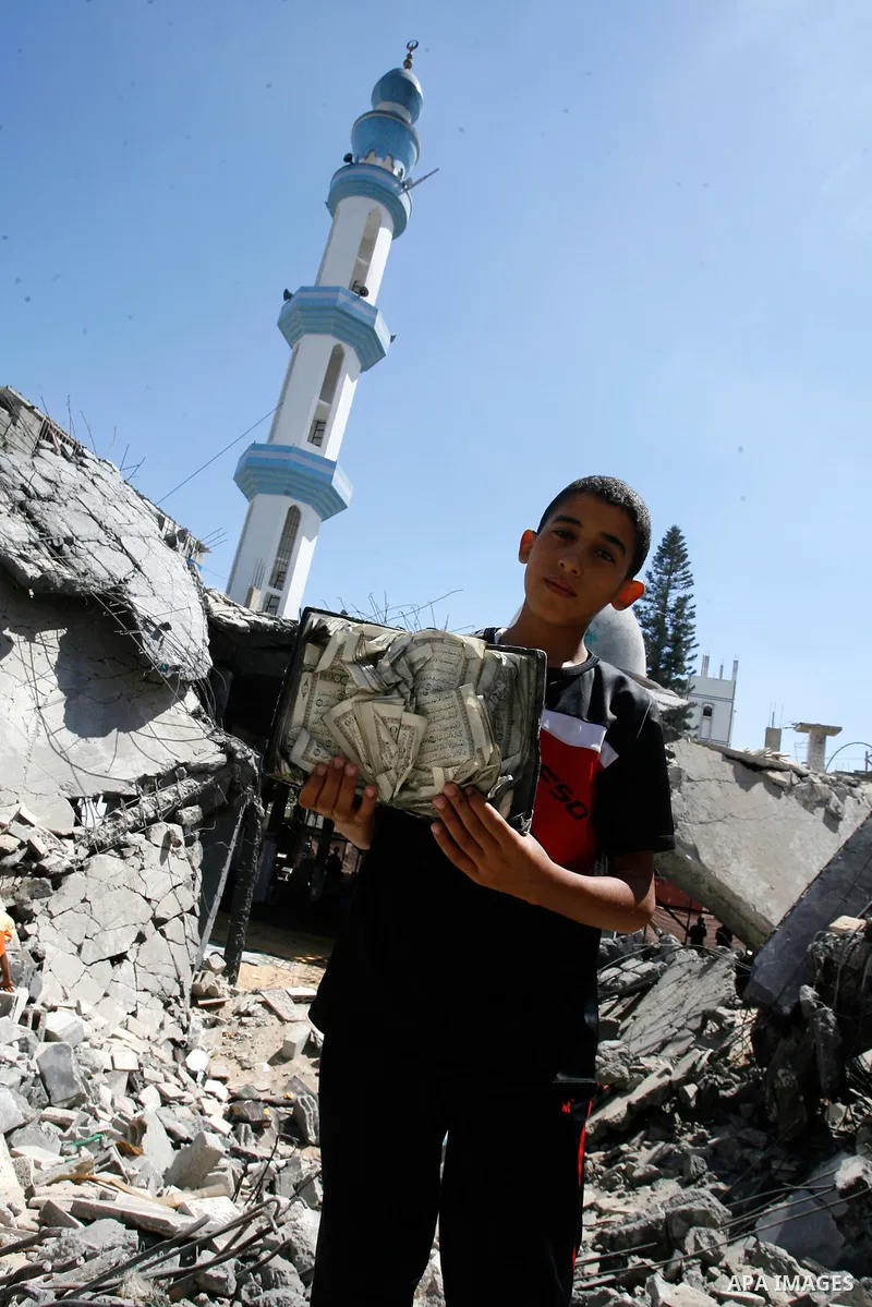 A Palestinian boy holds a copy of holy Quran as he stands on the rubble of the heavily damaged al-Faruq mosque which was destroyed by Israeli strikes during the summer's fierce offensive, in Rafah in the southern Gaza St...