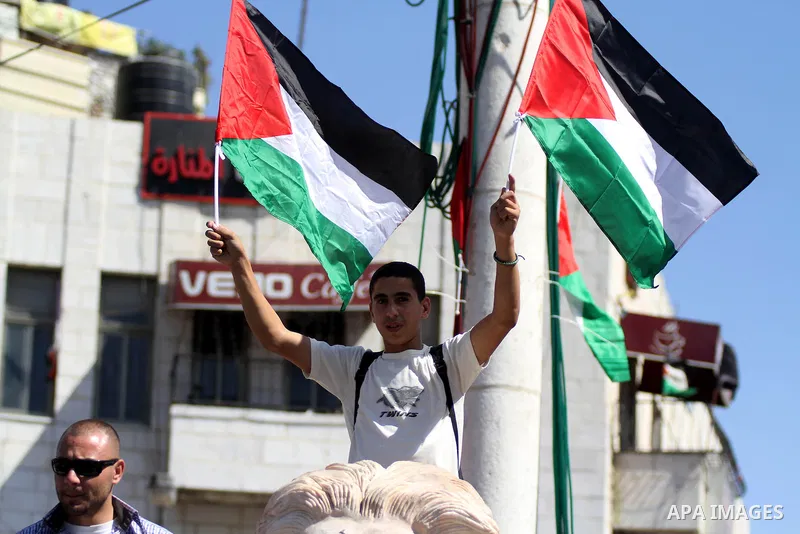 A Palestinian youth holds his national flags as he celebrates annual flag-raising, in the West Bank city of Ramallah on Sep. 22, 2014. Egypt will host a brief round of indirect talks this week between Israelis and Palest...