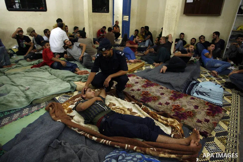 Palestinian migrants sit in a police building in Rafah after their arrival to the Palestinian side late at night in the southern Gaza strip, on September 23, 2014. Egyptian naval forces arrested would-be Palestinian immi...
