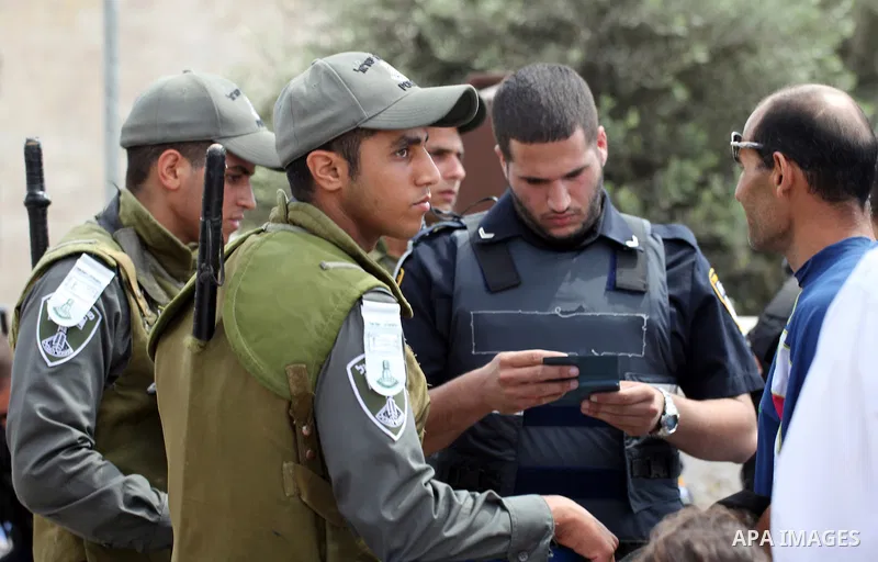 An Israeli policeman checks the documents of a Palestinian muslim as others block Palestinians from praying in the city's Al-Aqsa mosque, in the Ras Al-Amud neighborhood of East Jerusalem on Spe. 26, 2014. Israeli police...
