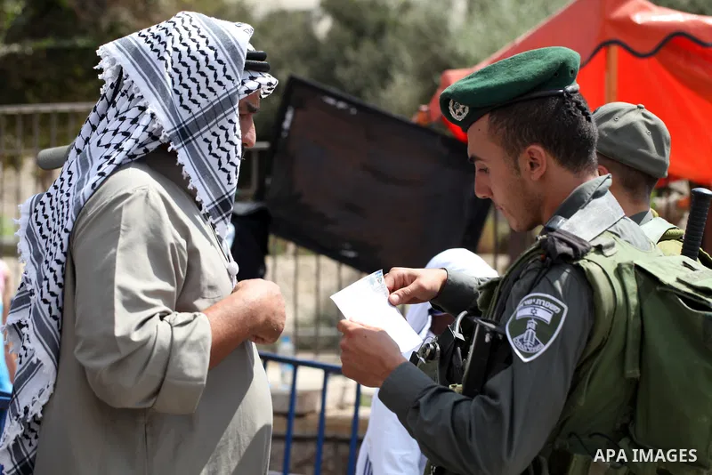 An Israeli policeman checks the documents of a Palestinian muslim as others block Palestinians from praying in the city's Al-Aqsa mosque, in the Ras Al-Amud neighborhood of East Jerusalem on Spe. 26, 2014. Israeli police...