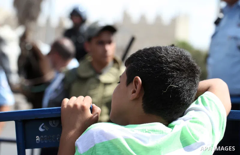 A Palestinian boy looks on as Israeli policemen block Palestinians from praying in the city's Al-Aqsa mosque, in the Ras Al-Amud neighborhood of East Jerusalem on Spe. 26, 2014. Israeli police stepped up security around...