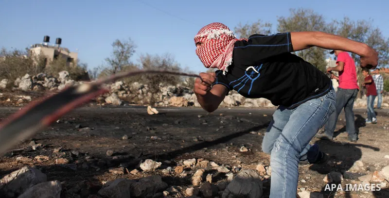 A Palestinian protester uses a slingshot to hurl a stone towards Israeli security forces during clashes at a protest against the Jewish settlement of Ofra, in the West Bank village of Silwad, near Ramallah September 26,...