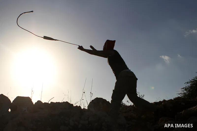 A Palestinian protester uses a slingshot to hurl a stone towards Israeli security forces during clashes at a protest against the Jewish settlement of Ofra, in the West Bank village of Silwad, near Ramallah September 26,...