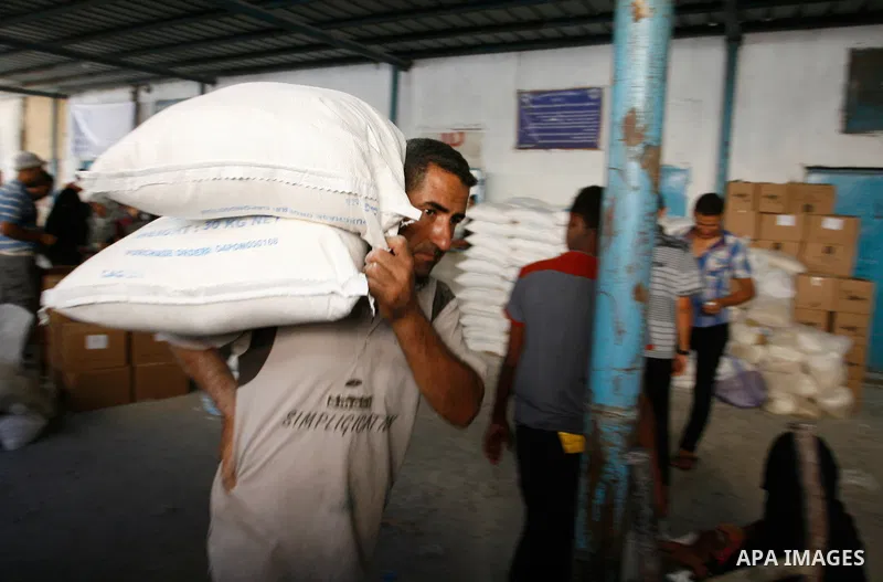 A Palestinian worker carries a sack of flour to be distributed to people at a United Nations food distribution centre in Rafah city in Gaza strip on Sept. 28, 2014. The aid was sent to the U.N. office to be distributed i...