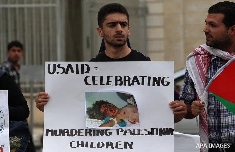 Palestinian students hold placards against the United states agency for international development "USAID" during the visit of American consul to al-Najah University in the West Bank city of Nablus, Spe. 29, 2014. Student...