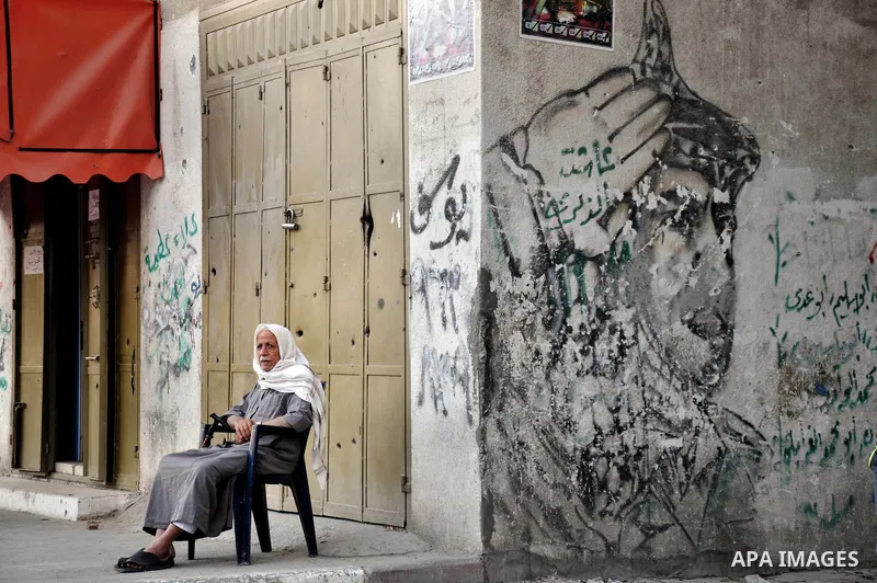 A Palestinian man sit in front of his damaged house in Al-Shaejaeiya neighbourhood in the east of Gaza City, 29 September 2014. Israeli Prime Minister Benjamin Netanyahu headed for New York on 28 September to respond to...