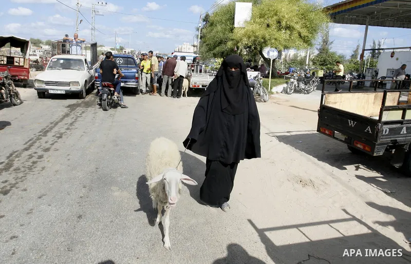 A Palestinian woman leads a goat at a livestock market, days before the major Muslim festival of Eid al-Adha, in Khan Younis in the southern Gaza Strip on October 1, 2014. During the first week of October, Muslims across...