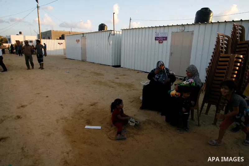 Palestinian women inspect their container donated by a charity organisation as temporary housing for whose houses were destroyed during a seven-week Israeli offensive, near the rubble of destroyed houses, in the east of...