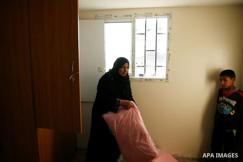 Palestinians inspect their container donated by a charity organisation as temporary housing for whose houses were destroyed during a seven-week Israeli offensive, near the rubble of destroyed houses, in the east of Khan...