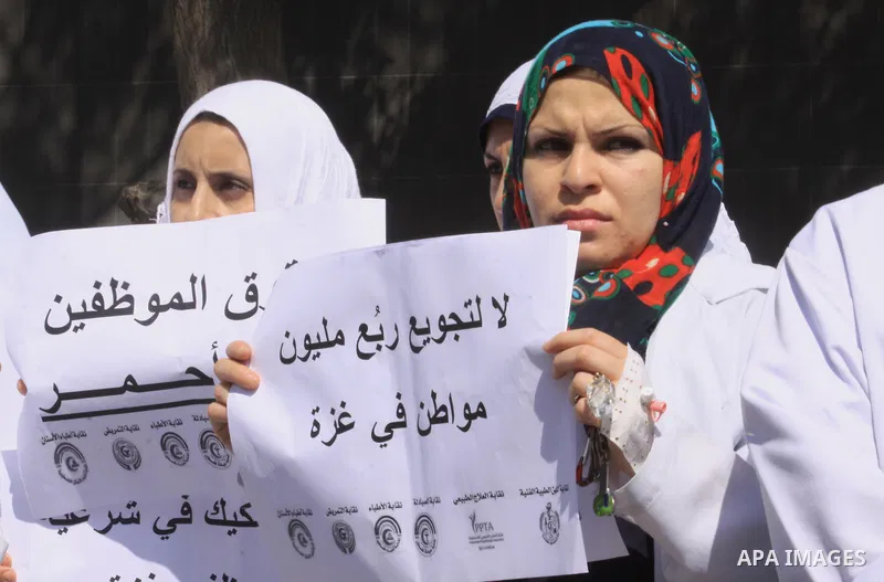 Palestinian Doctors of the formerly Hamas-run government in the Gaza Strip hold banners during a protest to demanding their salaries, in Gaza city, on October 2, 2014. Photo by Mohammed Asad