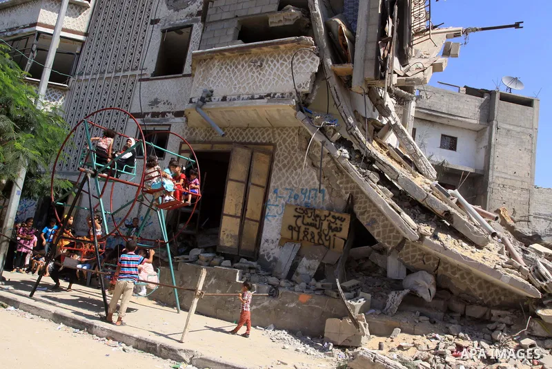 Palestinian children play on a swing near the rubble of houses that were destroyed during the seven-week Israeli offensive, in the Shejaia neighborhood east of Gaza City October 5, 2014, on the second day of the Muslim E...