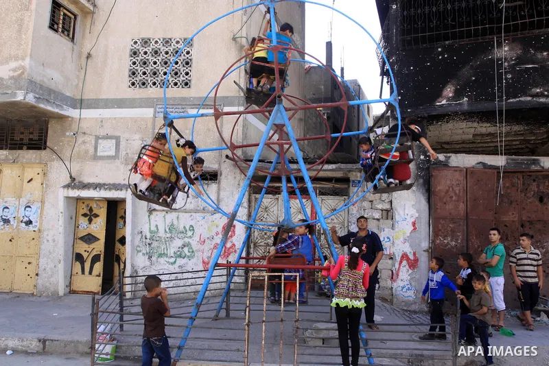 Palestinian children play on a swing near the rubble of houses that were destroyed during the seven-week Israeli offensive, in the Shejaia neighborhood east of Gaza City October 5, 2014, on the second day of the Muslim E...