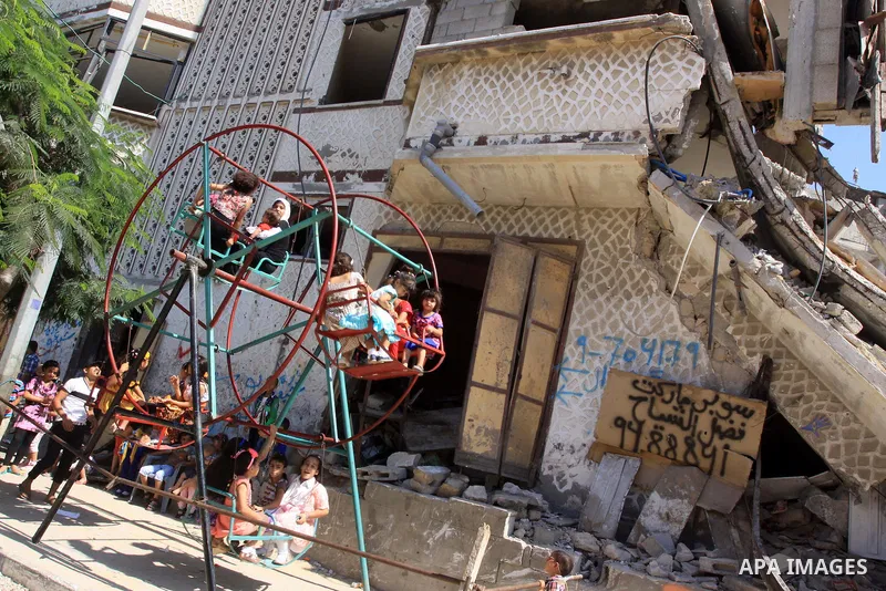 Palestinian children play on a swing near the rubble of houses that were destroyed during the seven-week Israeli offensive, in the Shejaia neighborhood east of Gaza City October 5, 2014, on the second day of the Muslim E...