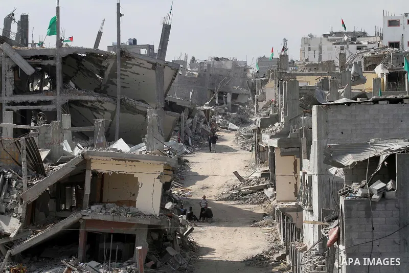 Palestinians walk next to the destroyed houses that were destroyed during the devastating 50-day war between Israel and Hamas at Al-Shojae'ya neighborhood east of Gaza City on October 12, 2014. Ahead of a donors conferen...