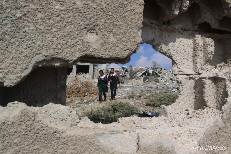 Palestinian students walk next to the destroyed houses that were destroyed during the devastating 50-day war between Israel and Hamas at Al-Shojae'ya neighborhood east of Gaza City on October 12, 2014. Ahead of a donors...