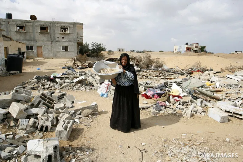 A Palestinian woman stands amid the rubble of her home which was destroyed during the 50-day conflict between Hamas militants and Israel, in the southern Gaza Strip town of Rafah on October 12, 2014. Some 50 countries ar...